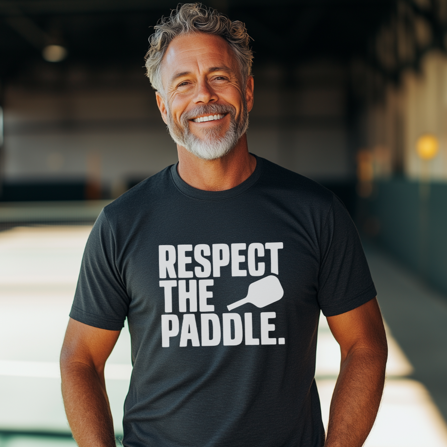 Man wearing a dark grey pickleball tee that says Respect the Paddle
